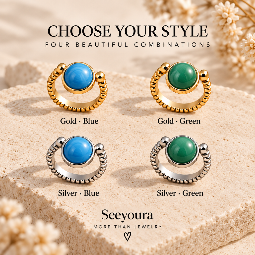 Four ring options displayed on a textured stone surface with decorative dried flowers. The rings feature round blue or green stones set in gold or silver bands, with text labels reading Gold-Blue, Gold-Green, Silver-Blue, and Silver-Green.