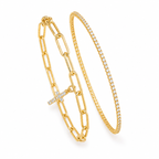 Two gold bracelets on a white background: one with a paperclip chain and cross charm set with small clear stones, and one with a thin pavé-set bangle.