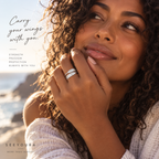 A woman outdoors at sunset wearing two silver bands on her hand, with text on the left reading 'Carry your wings with you.' and 'STRENGTH FREEDOM PROTECTION ALWAYS WITH YOU.