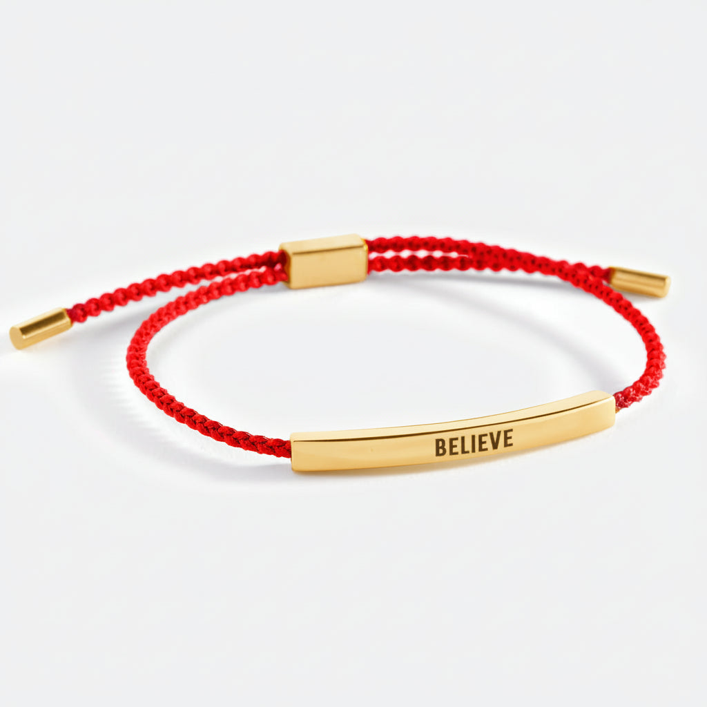 Red bracelet with rose gold clasp and 'BELIEVE' bar on a white background
